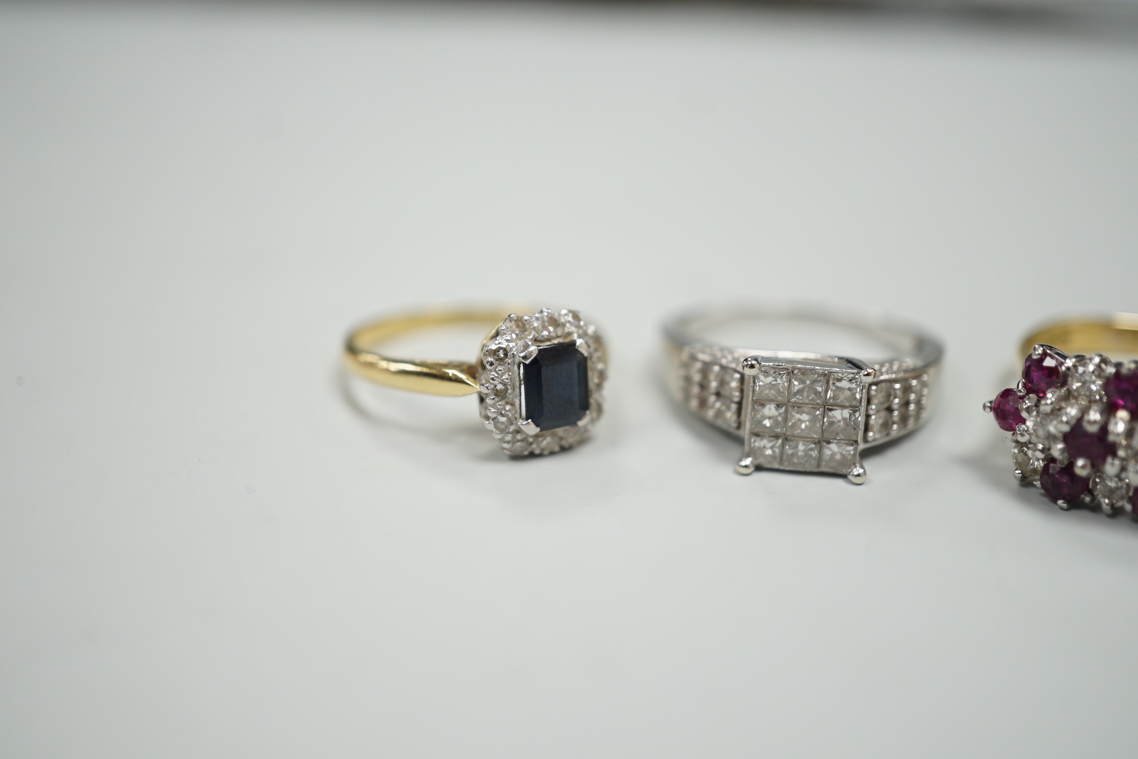 Three assorted modern gem set rings, including white metal and diamond cluster tablet ring with diamond set shoulders, an 18ct gold, sapphire and diamond cluster set ring and an 18ct gold ruby and diamond set cluster rin